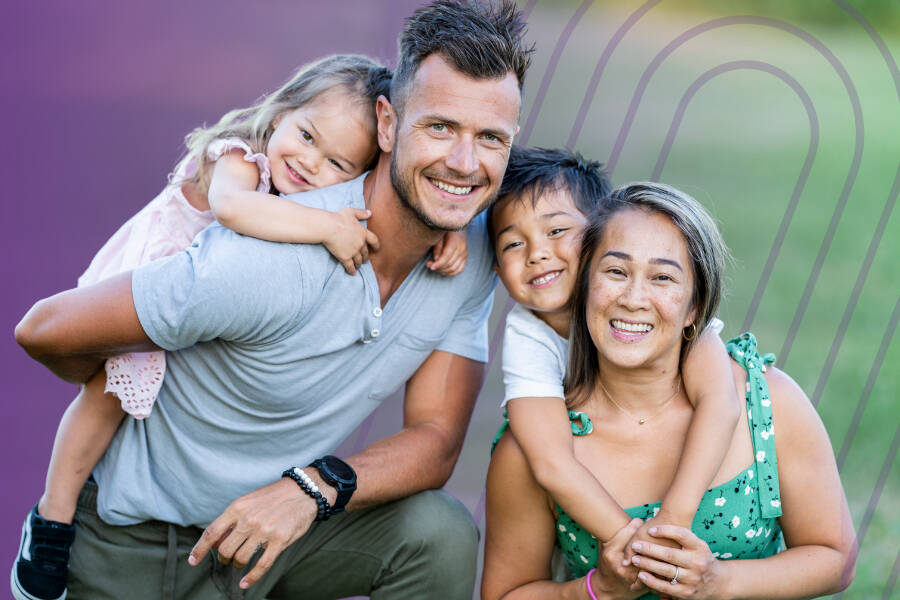 A family of four smiling and hugging